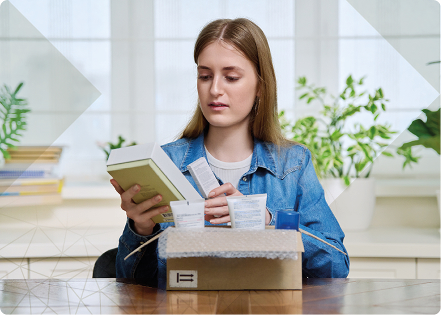 Mujer desempaquetando productos de belleza de una caja de cartón, ilustrando el papel de la cadena logística del lujo en la experiencia del cliente.